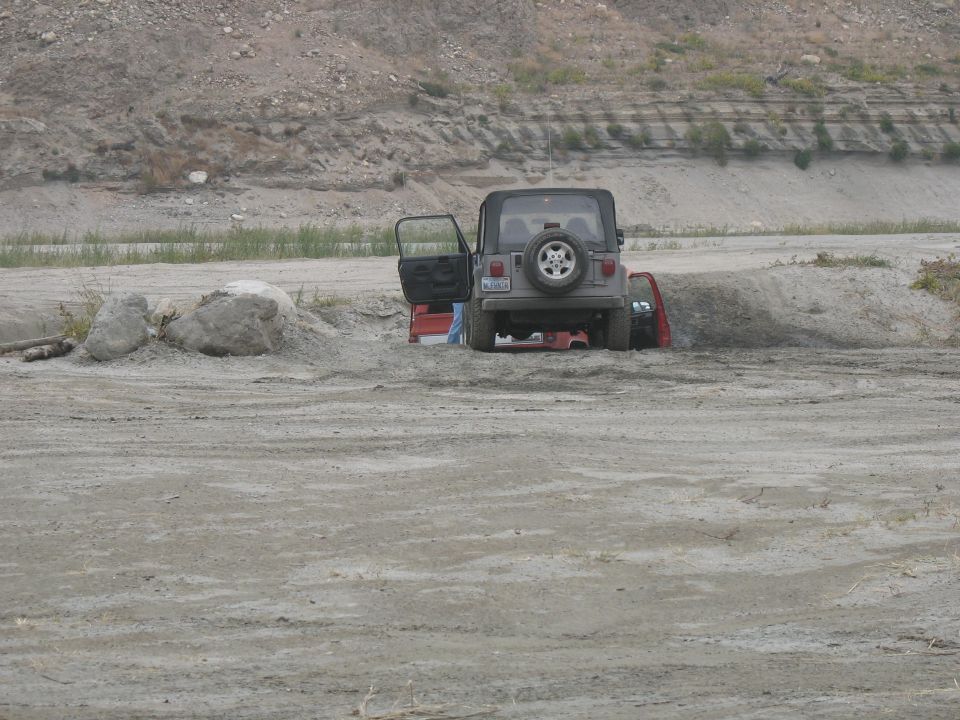 Jeep Wrangler with door open stuck in sand, another vehicle partially visible behind it