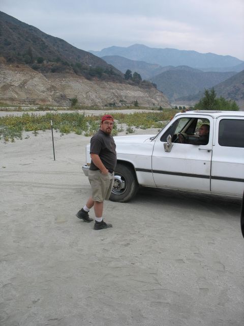 1987 Ford Bronco - Man standing next to a white SUV in a dry, mountainous area.