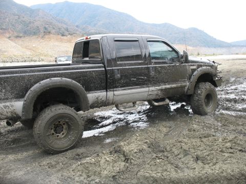 1987 Ford Bronco - Pickup truck is stuck in mud, with mountains visible in the distance.
