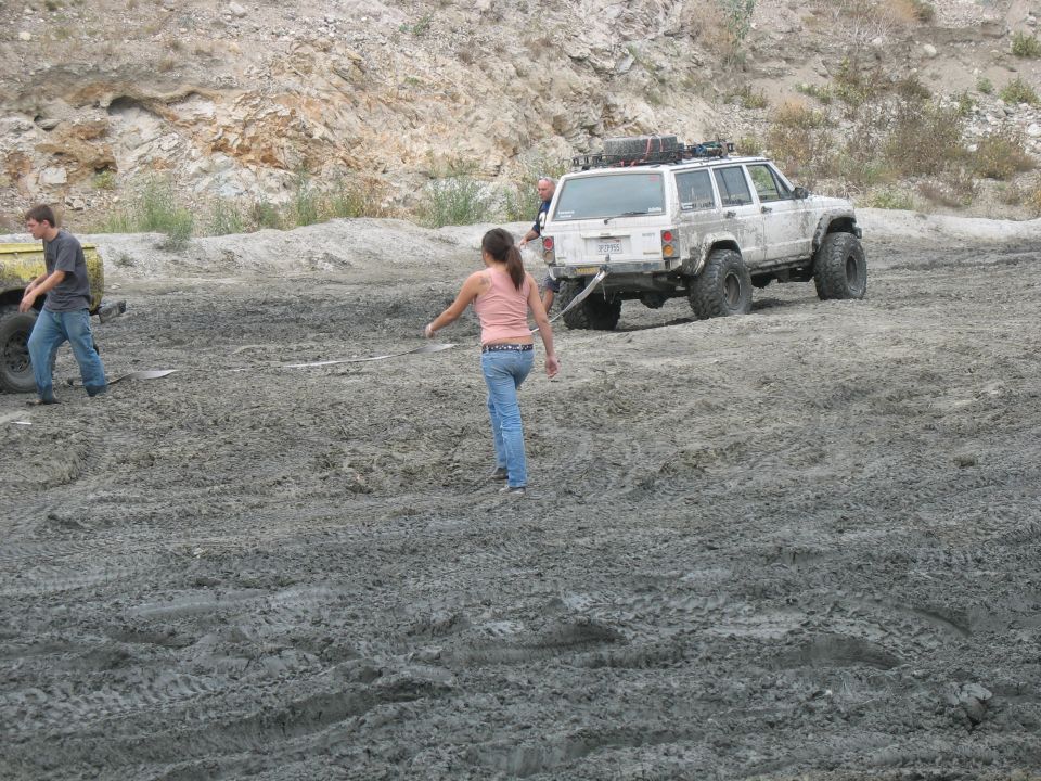 White Jeep Cherokee XJ stuck in mud, with people around