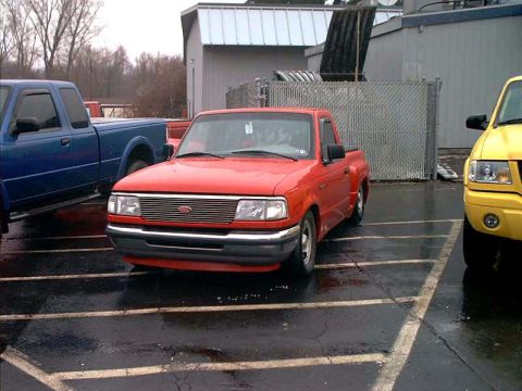 2000 Ford Crown Victoria - Red Ford Ranger pickup truck parked in a lot with other vehicles visible.