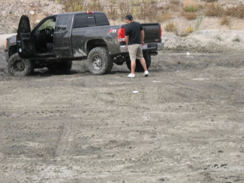 Black pickup truck with lifted suspension and open driver's door parked on dirt