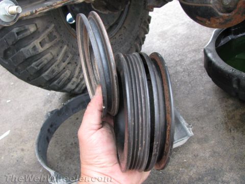 1987 Suzuki Samurai - Close-up of engine pulleys and a belt, with a tire and oil pan visible in the background.