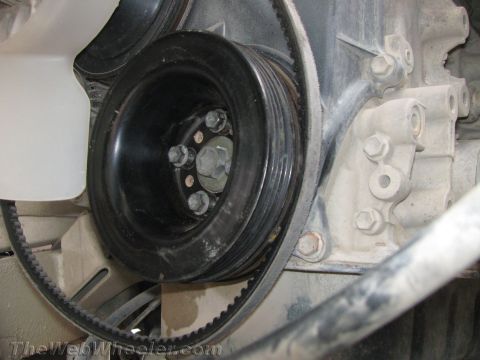 1987 Suzuki Samurai - Close-up view of an engine's pulley system, showing a ribbed belt wrapped around a grooved pulley.