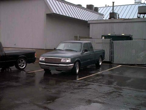 2000 Ford Crown Victoria - A dark green pickup truck is parked in a lot next to a black pickup truck.