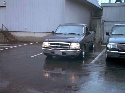 2000 Ford Crown Victoria - Two pickup trucks are parked in a lot after rain, one is a Ford Ranger.