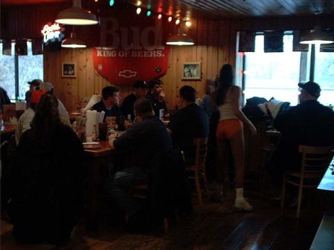 2000 Ford Crown Victoria - A group of people are gathered inside a dimly lit bar, with a prominent Budweiser sign visible.