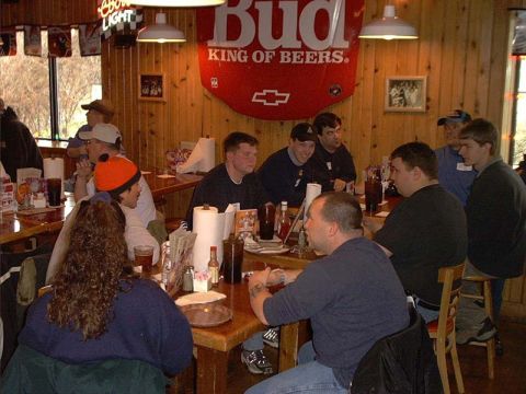 2000 Ford Crown Victoria - A group of people are seated at tables in a restaurant, with a prominent Budweiser sign in the background.