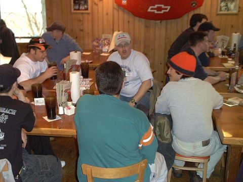 2000 Ford Crown Victoria - A group of people are seated at tables in what appears to be a casual dining establishment, with drinks and condiments visible.