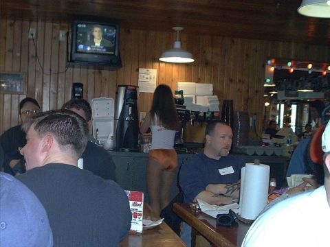 2000 Ford Crown Victoria - Interior of a wood-paneled Hooters restaurant with patrons seated at tables, a server in the standard white tank top and orange shorts work…