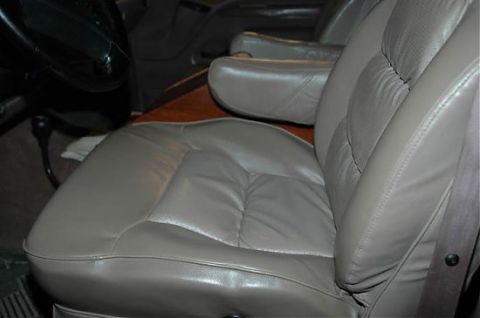 1995 Ford C-350 (Centurion Conversions) - The interior of a van shows plush captain's chairs and a wooden trim detail.