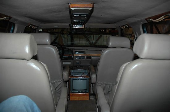 Gray leather captain's chairs and center-console TV inside a Ford Centurion van conversion interior