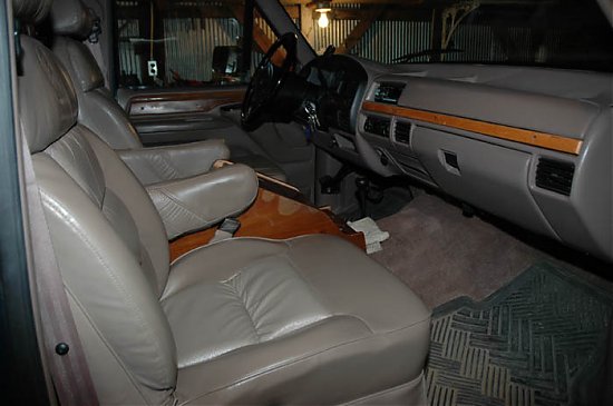 Gray-tan leather bucket seats and woodgrain dash inside a 1990s Ford truck, passenger-side view
