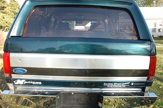 Rear tailgate of dark green Ford SUV with Ford oval badge and Nautiques decal