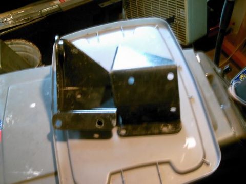 1986 Ford Bronco - Two metal brackets are shown resting on a white plastic container, likely for sale or storage.