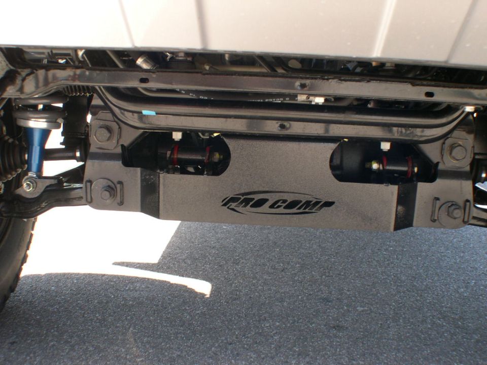Vehicle undercarriage with Pro Comp branded skid plate and blue shock absorber