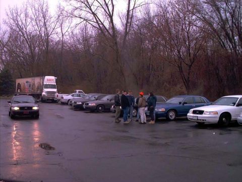 2000 Ford Crown Victoria - A group of people stand near several Ford Crown Victoria police cars in a wet parking lot.