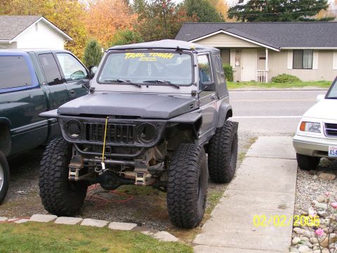 1988 Suzuki Samurai - This heavily modified off-road vehicle features oversized tires and a custom front end. A "TRAIL TOUGH" sticker is visible on the windshiel…