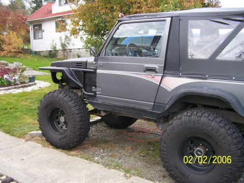 1988 Suzuki Samurai - Modified 1988 Suzuki Samurai parked in a driveway with large off-road tires.