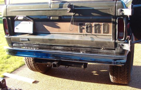 1975 Ford Bronco - The rear of a 1975 Ford Bronco is visible, a hitch receiver and the iconic Ford tailgate lettering.