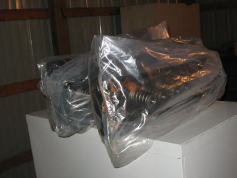 1900 Ford Wagon - Engine components are stored in plastic wrap inside a building.