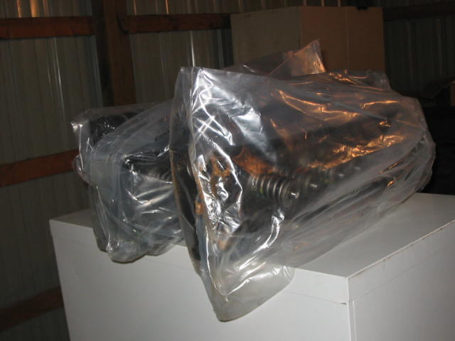 Engine parts wrapped in plastic on a white surface