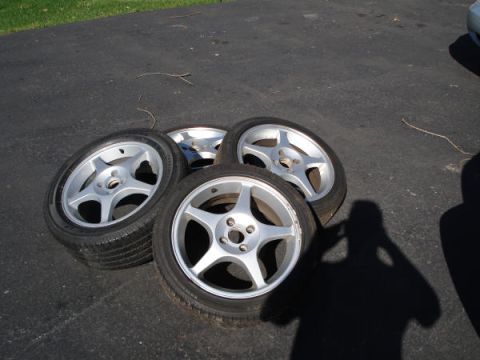 1979 Ford Bronco - Four aftermarket alloy wheels with tires are resting on a paved surface.