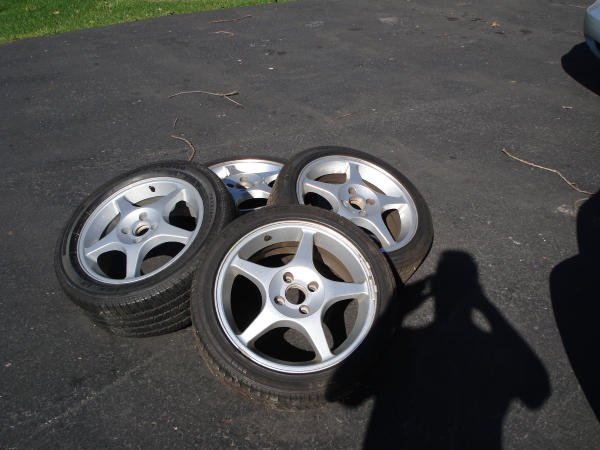 four alloy wheels with tires on asphalt