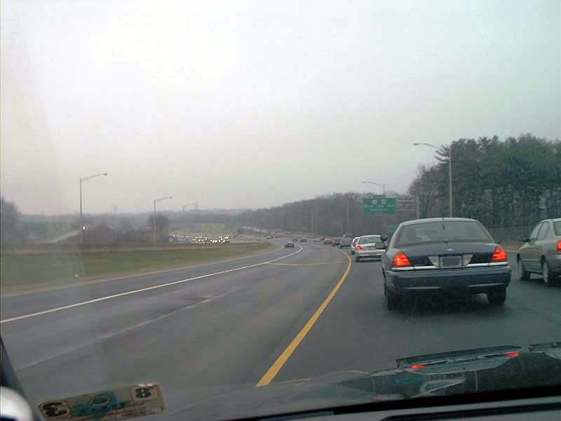Dark blue Ford Crown Victoria seen through a windshield on a wet divided highway