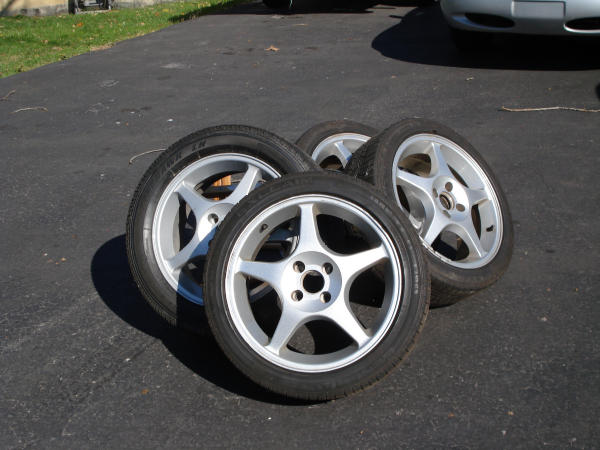 four alloy wheels with tires on pavement