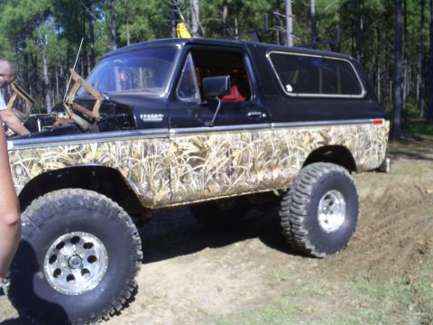 1979 Ford Bronco - This lifted Ford Bronco features a camouflage wrap and aggressive off-road tires, suggesting it's built for terrain.