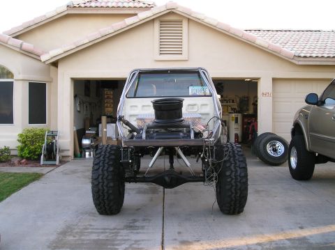 1986 Toyota Hilux - This heavily modified truck chassis, viewed from the rear, features large off-road tires and appears to be undergoing customization.