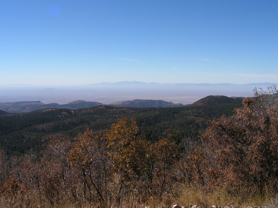 Mountainous landscape with dry brush in the foreground and distant hazy mountains under a clear blue sky