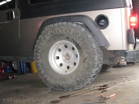 1987 Suzuki Samurai - Close-up of a Jeep Wrangler's rear wheel and fender area, showing the fuel filler cap.