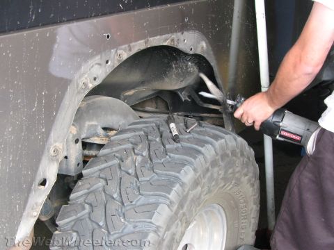 1987 Suzuki Samurai - A person uses a reciprocating saw to cut away a fender flare on a vehicle's wheel well.