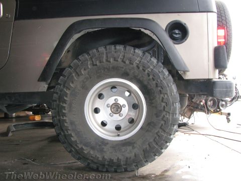 1987 Suzuki Samurai - Close-up of a Jeep Wrangler's rear tire and fender assembly, showing off-road tire tread.