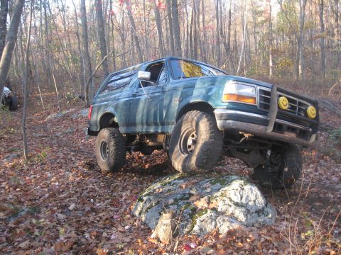 1996 Ford Bronco - This lifted 1996 Ford Bronco is navigating a rocky, wooded path during autumn.