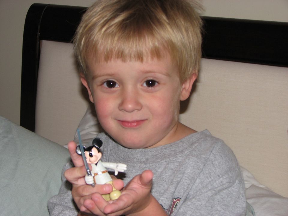 Child holding Mickey Mouse toy with lightsaber