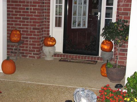 1991 Ford Bronco - Halloween pumpkins are displayed on a porch next to a front door and a potted plant.