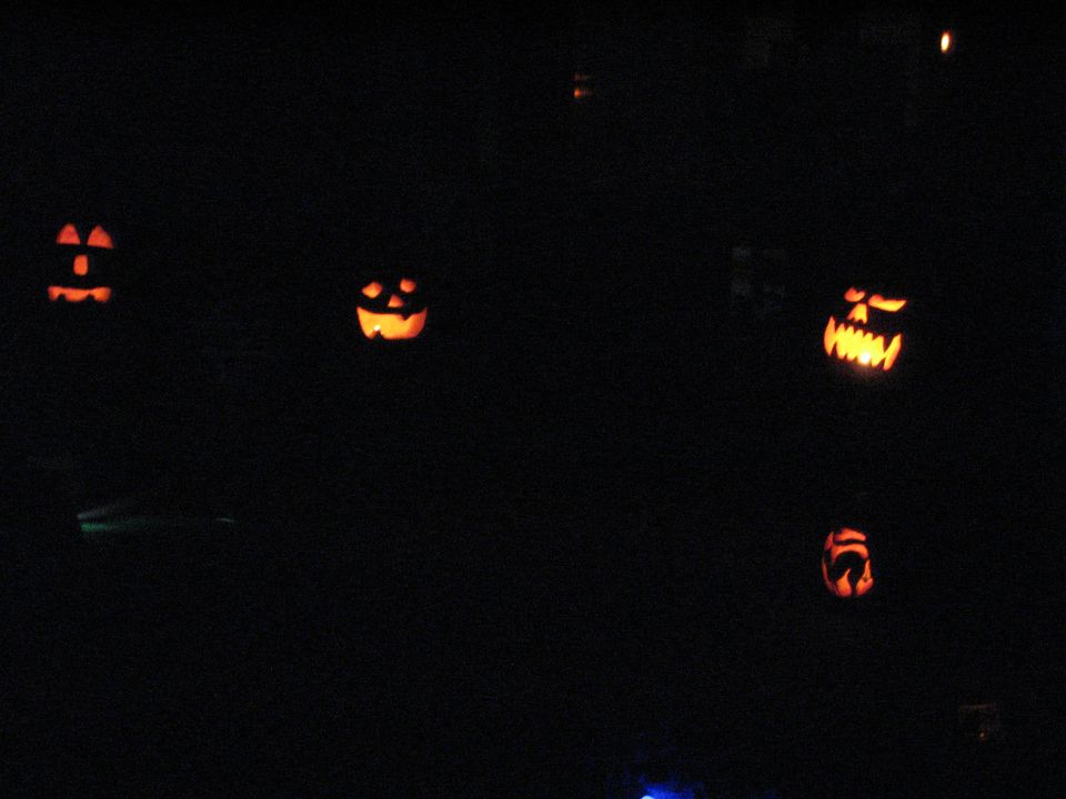 several carved pumpkins glowing in the dark