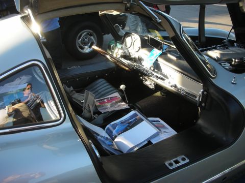 1998 Ford Crown Victoria - View into a classic gullwing coupe's cabin showing the raised door, chrome dash trim, gauges and car-show brochures on the seat.