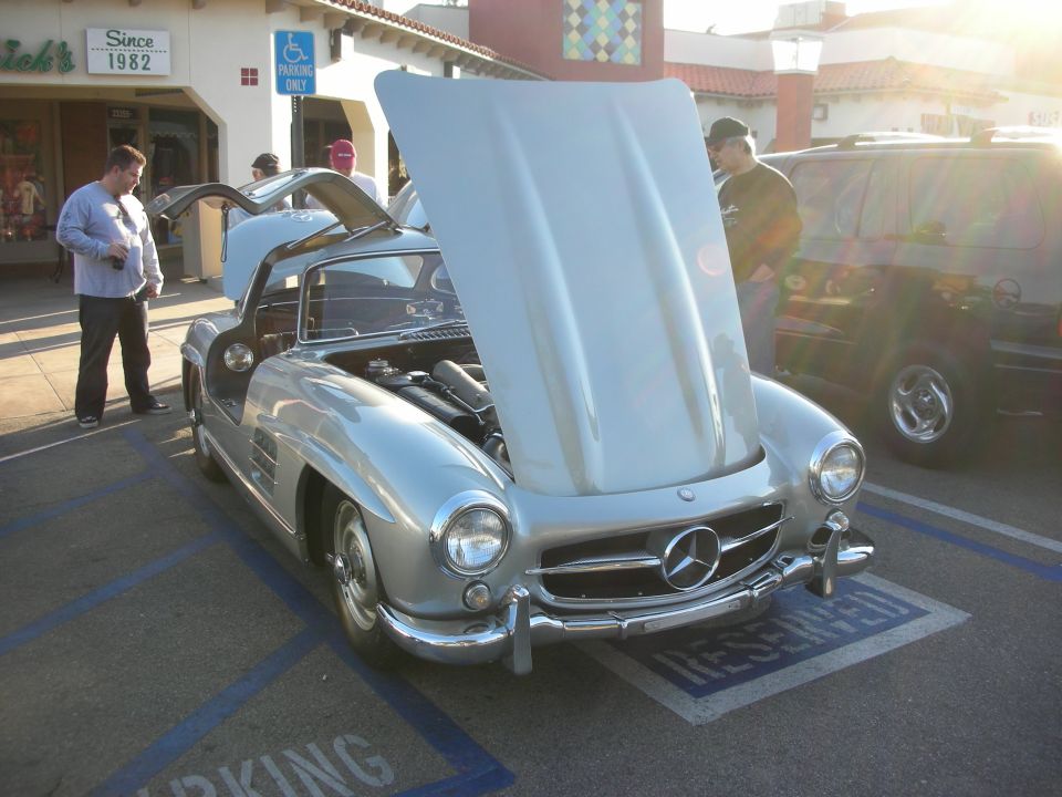 Silver Mercedes-Benz 300SL gullwing-style roadster with hood up at an outdoor car show