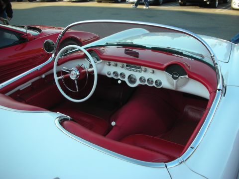 1998 Ford Crown Victoria - Cockpit of a vintage Corvette roadster with a white steering wheel and red and white interior trim.