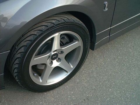 2000 Ford Crown Victoria - Close-up of a gray Ford Mustang Cobra front wheel with a five-spoke SVT alloy, low-profile tire and Cobra fender badge.