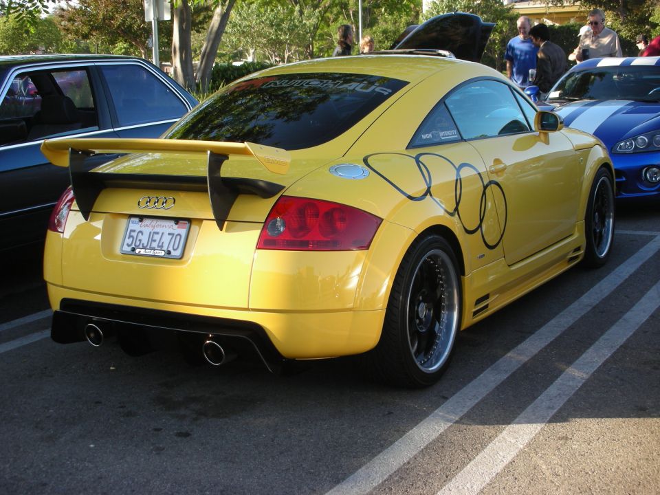 Yellow Audi TT coupe rear three-quarter with rear wing and black wheels