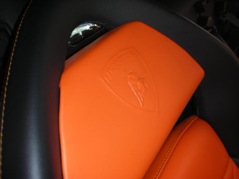 1998 Ford Crown Victoria - Detail of an orange leather Lamborghini seat showing the embossed shield-and-bull crest.