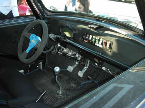 1998 Ford Crown Victoria - Bare race-car cockpit with a suede steering wheel, digital gauge, switch panel and a metal shifter.