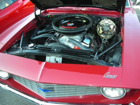 1998 Ford Crown Victoria - Open engine bay of a red Camaro showing a V8 with a 427 air cleaner lid and a Camaro emblem on the radiator support.