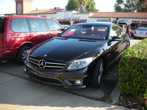 1998 Ford Crown Victoria - black Mercedes-Benz CL 63 AMG coupe parked front three-quarter in a strip-mall parking lot near a fitness center.