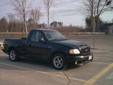 2000 Ford Crown Victoria - A black 1999 Ford F-150 Lightning pickup truck is parked at an outdoor venue.